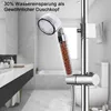 A shower head with beads inside, mounted on a shower rail in a bathroom. Produktbild-Vorschau