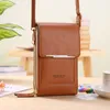 A brown crossbody bag is displayed on a table with a blurred background. Produktbild-Vorschau