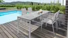 A modern outdoor dining set with a table and chairs next to a swimming pool on a wooden deck. Produktbild-Vorschau
