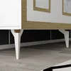 A close-up view of the legs and bottom of a white and gold cabinet. Produktbild-Vorschau