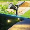 A solar-powered spotlight and ground lights illuminate a garden path at dusk. Voir les images du produit