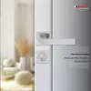 A close-up of a modern door handle and lock set, with a blurred interior scene in the background. Produktbild-Vorschau
