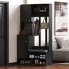 A black entryway cabinet with a bench and shoe storage, placed in a room next to a door and a sofa. Voir les images du produit