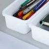 Close-up of two white plastic storage bins filled with colorful markers and a small book. Náhľad obrázku produktu