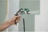 A hand holding a paint sprayer spraying paint on a wall. Náhled obrázku produktu