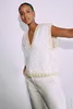 A woman is posing in a studio setting against a white background, wearing a knitted vest and trousers. Produktbild-Vorschau