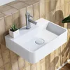 A modern white ceramic wall-mounted sink with a silver faucet is shown against a tiled wall. Náhled obrázku produktu
