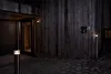 Exterior view of a modern wooden house at night, with a garage door, entrance, and house number visible. Produktbild-Vorschau