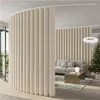 A curved room divider made of beige fabric panels separates a living area with a sofa and coffee table from another space, possibly a hallway or entrance, with a Christmas tree visible in the background. Produktbild-Vorschau