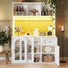 A white kitchen cabinet with glass doors, filled with kitchenware and decorative items, illuminated by a yellow LED light. Náhľad obrázku produktu