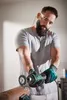 A man is using a power tool to work on a metal pipe. Produktbild-Vorschau