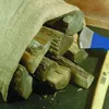 A burlap sack filled with cut logs, with an axe nearby. Produktbild-Vorschau