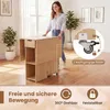 A woman is interacting with a wooden folding table in a room. The image also includes close-ups of the table's wheels and text highlighting its features. Náhľad obrázku produktu
