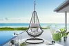 A hanging chair is set up on a patio overlooking the ocean. Produktbild-Vorschau