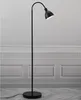 A black floor lamp stands in a room with white paneled walls and a marble-patterned floor. Náhled obrázku produktu