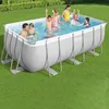 A family is enjoying themselves in a rectangular above-ground swimming pool set up on a grassy lawn. Produktbild-Vorschau