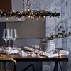 A table setting with wine glasses, plates, and decorative elements, including a string of lights. Podgląd zdjęcia produktu