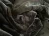 A close-up view of a dark, soft, textured fabric, likely a blanket or bedding. Produktbild-Vorschau