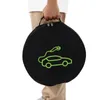 A person is holding a black circular bag with a green outline of an electric car and charging cable on it. Podgląd zdjęcia produktu