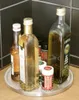 A rotating tray with several bottles of oil and spices on a wooden surface, with a black tiled background. Anteprima dell’immagine prodotto