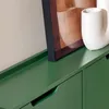 A close-up view of a dark green cabinet with a white vase and a framed picture on top. Náhľad obrázku produktu