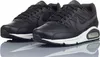 A pair of black Nike Air Max Command Leather sneakers are shown from a slightly elevated front-left angle, resting on a reflective surface. Voir les images du produit