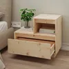 A wooden nightstand next to a bed. Produktbild-Vorschau