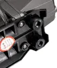 A close-up view of a black plastic component with silver screws and black rubber feet, attached to a gray device. A red and white sticker with black text is visible on the plastic component. Náhľad obrázku produktu