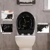 A toilet seat with a black and gold marble pattern is shown on a toilet in a bathroom. Insets highlight features like easy cleaning, non-slip buffers, and stable mounting. Produktbild-Vorschau
