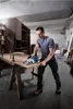 A man is using a circular saw to cut a piece of wood in a workshop. Produktbild-Vorschau