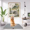 A golden retriever dog sits on a gray orthopedic dog bed in a well-decorated room with a painting on the wall and a desk with a computer. Produktbild-Vorschau