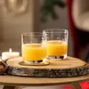 Two glasses of orange juice on a wooden board with a candle and a walnut. Produktbild-Vorschau