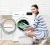 A woman is placing a colorful bath mat into a washing machine. Produktbild-Vorschau