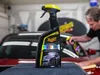 A person is detailing a car in a garage, with a bottle of car cleaning product in the foreground. Produktbild-Vorschau