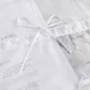 A close-up of a white fabric item with text and a white ribbon tied in a bow. Produktbild-Vorschau
