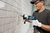A man is drilling a hole in a tiled wall. Podgląd zdjęcia produktu