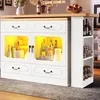 A white kitchen island with a wooden countertop, illuminated glass cabinets displaying bottles and containers, and a side shelving unit filled with jars. Anteprima dell’immagine prodotto