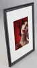 A framed picture of a woman with red hair and red flowers. Produktbild-Vorschau