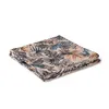 A folded textile with a tropical leaf pattern on a white background. Produktbild-Vorschau