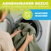 A person is putting a green blanket into a washing machine. Produktbild-Vorschau