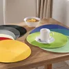 A table setting with multiple colorful placemats, a bowl of cereal, and a cup of coffee. Produktbild-Vorschau