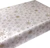 A close-up, angled view of a white tablecloth with a repeating pattern of gold snowflakes and stars. Produktbild-Vorschau