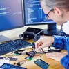 A person is working on a drone and electronics project at a desk with computers and VR goggles. Anteprima dell’immagine prodotto