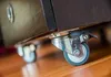 A close-up view of casters attached to a piece of furniture. Náhled obrázku produktu