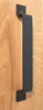 A close-up shot of a black door handle mounted on a wooden door. Produktbild-Vorschau