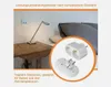 A bedside table with a lamp and a travel adapter shown in a circular inset. Produktbild-Vorschau