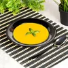 A bowl of soup with a basil leaf garnish on a placemat. Podgląd zdjęcia produktu