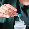 A person's hand is holding a teal-colored baby bottle accessory over an open baby bottle. Produktbild-Vorschau