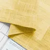A close-up view of yellow fabric with a textured weave, folded over a white surface with some text visible underneath. Voir les images du produit