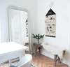 A festive Christmas scene with a large mirror, a white table and chair, and a wooden bench with a fluffy throw. An advent calendar hangs on the wall. Podgląd zdjęcia produktu